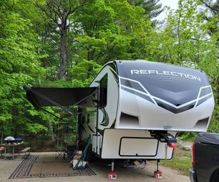 Clear photo of a seasonal full-hookup RV parked at a campsite with picnic table and forested background; appears on the site’s Seasonal Rentals page illustrating on-site RV sites and amenities.