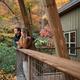 Image of guests on a cabin balcony with fall foliage — conveys guest experience, cabin deck scale and seasonal scenery on the property (gallery/marketing image).