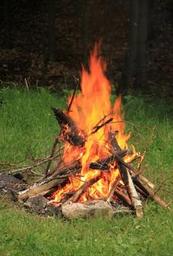 Close photo of a campfire on grass — shows on-site recreation/camping activity and matches Recreation page content.