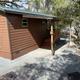 Exterior shot of a specific cabin unit (side and entry area, gravel parking and fire ring) — helps illustrate individual cabin layout and site features from the cabins gallery.