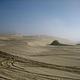 Sand dunes covered in OHV tracks, fog almost burned off.