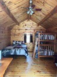 Cozy wooden cabin bedroom with bunk and double beds.