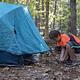 A young man sets up a blue tent