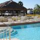 Clear photo of the resort swimming pool area with lounge chairs, tiki hut, and RVs visible behind the pool — shows pool amenity and relation to RV sites (from the property page).