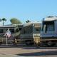 Close view of lined RV sites with motorhomes and small dividers; supports the park’s onsite RV accommodations and appears to be the same property (same style of pads and background desert landscape).