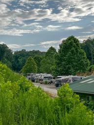View of RV loop/sites with multiple RVs and trees — clearly depicts the resort’s RV camping area and site layout (from the RV sites page).