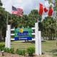 Clear photograph of the resort entrance sign and flagpoles with surrounding landscaping and palms — good identifying exterior shot from the property homepage (entrance image).