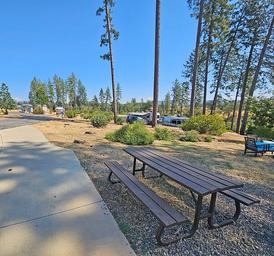 Picnic area foreground with park benches and RVs visible in the background — highlights onsite picnic/facility area and nearby campsites (from the property page).