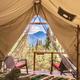 View from inside a tent framing distant mountains — useful interior-to-exterior shot demonstrating tent layout, bed setup and the scenic mountain views offered on-site (used on property pages).