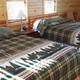 Interior bedroom with two beds in a wood-paneled rental unit — clearly from the Rentals page, shows on-site lodging accommodations.