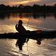 An angler casts at sunset while seated in a kayak