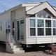 Model park home on gravel pad with adjacent RV visible — useful for showing available accommodations and site appearance (source page: Rates).