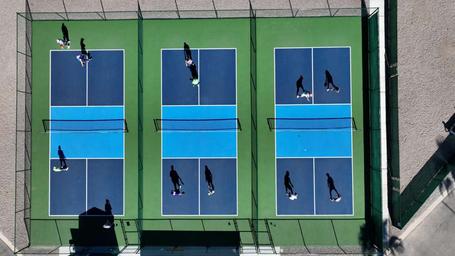 Overhead shot of multiple pickleball/tennis courts in use — highlights on-site recreational facilities available to guests.