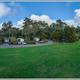 Wide panoramic view of multiple RV sites, open lawn and surrounding trees — useful for showing campsite arrangement and ambience (homepage image).