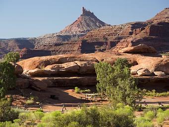 A picnic table adjacent to Hamburger Rock geologic feature with a Six Shooter peak in the background.