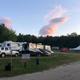 Clear photo of RVs, picnic table, signage and open campground area — good overview of RV/drive-up sites (from homepage gallery).