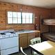 Cabin interior showing gas range, bunkbeds, table and dry sink 