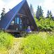 Woman sitting on porch of Shakes Slough 2 Cabin with grass in front and trees in background