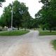 Overview of campground road/drive lanes and RV sites — shows gravel roads, site signage and mature trees, useful for displaying the park layout and RV pitch style (from the gallery).