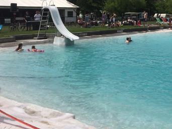 Clear photo of the campground swimming pool with slide and surrounding lawn/chairs — shows on-site amenity; appears on site media for the park's pool.