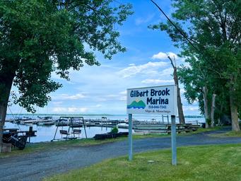 Photo of the Gilbert Brook Marina sign with docks and boats visible — directly from the Marina page, shows on-property marina facilities.