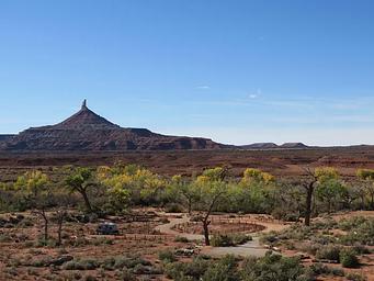 Panoramic view of the desert campground with a ribbon of cottonwood trees and Six Shooter Peak in the background.
