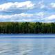Wide lake view across calm water with tree-lined shore — clear scenic photo of the resort's waterfront. Found on the site's Home page (Lake-tom image), supporting that this is the property's lake scenery.