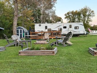 Shows an arranged seasonal site with deck, firepit seating and RV in the background — good detail of typical site amenities (from seasonal sites page).