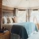 Interior bedroom of a safari tent showing bed, windows and tent structure — clearly represents the on-site lodging offering.