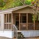 Close view of a cabin/rental unit with porch set beside wooded hillside — useful to show on-site rental accommodation; from the property gallery.