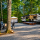 Clear photograph of a gravel RV/site setup with seating, firepit, and wooded surroundings — good representation of the campground’s RV/campsite accommodations; sourced from the site Home page.