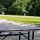 Picnic table sits on gravel tent pad with bathhouse in background