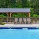 Refreshing resort swimming pool with fountains and outdoor seating pavilion surrounded by trees.