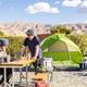 Tent campsite on a gravel pad with picnic table, shade plantings and desert mountain backdrop — good view of tent camping areas and surrounding scenery on the KOA grounds (from the campground waystostay photos).