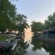 Narrow waterfront channel with parked boats, docks and shore buildings framed by trees — shows the resort’s marina/boat mooring area and appears on the property’s photo gallery pages.
