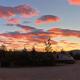 Sunset scene with RVs and parked vehicles silhouetted against colorful sky — demonstrates evening atmosphere and on-site RV spots (homepage/gallery context).