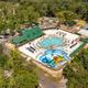 Aerial overview showing the resort layout: central pool complex with slides, surrounding facilities, courts, and RV/campsite areas — clearly the property grounds (image appears on the park homepage/gallery).