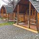 Row of small log cabins on gravel pads with porches; clearly shows the property’s cabin accommodation (amenities page image).