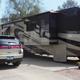 Wide exterior shot of a large motorhome in a paved site with adjacent RVs and park landscaping — good depiction of site size and parking configuration.