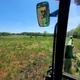 View from inside a tractor cab looking over a grassy field with a clear blue sky.
