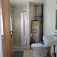 A bathroom with toilet, sink, water heater, and shower.