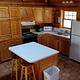 View of the kitchen in the Hillside Cabin with wood cabinents refrig, stove, and island bar with 2 stools