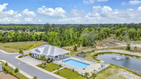 Aerial perspective focused on clubhouse, pool and adjacent pond with surrounding landscaping — indicated on the site as a pool/clubhouse aerial (social image on main page).