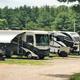 Row of parked RVs on gravel pads with trees in background — representative of the RV/trailer & Big Rig camping area shown on the RV camping page.