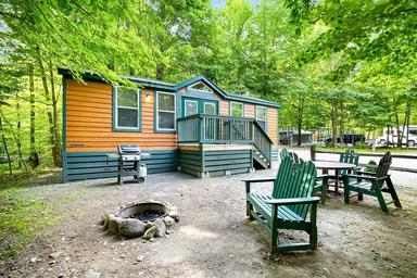 Cabin exterior with Adirondack chairs and a fire ring — clearly shows a cabin site and adjacent grounds from the campground's lodging photos.