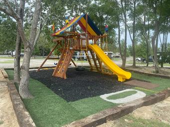 Playground equipment set among RV pads visible in background — shows family-friendly amenities and nearby campsite layout.