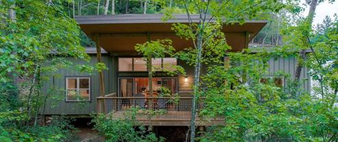 Frontal exterior of a cabin set in forested surroundings, good overall property view highlighting building design and site vegetation (used on the property’s landing page).