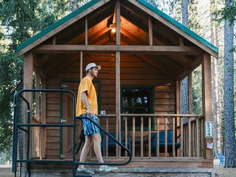 Small cabin on a wooded site with porch and site marker (S24) — useful depiction of on‑site cabin accommodation options (from Accommodations page).