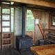 Interior of wood cabin with shelves, tables, stove and ladder to loft