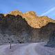 Gravel dirt road with a parallel roadside campsite surrounded by dark canyon walls.